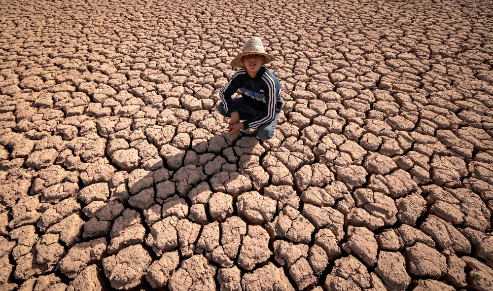 A child crouches over cracked earth at al-Massira dam in Ouled Essi Masseoud village, some 140 kilometres (85 miles) south from Morocco's economic capital Casablanca. (AFP)