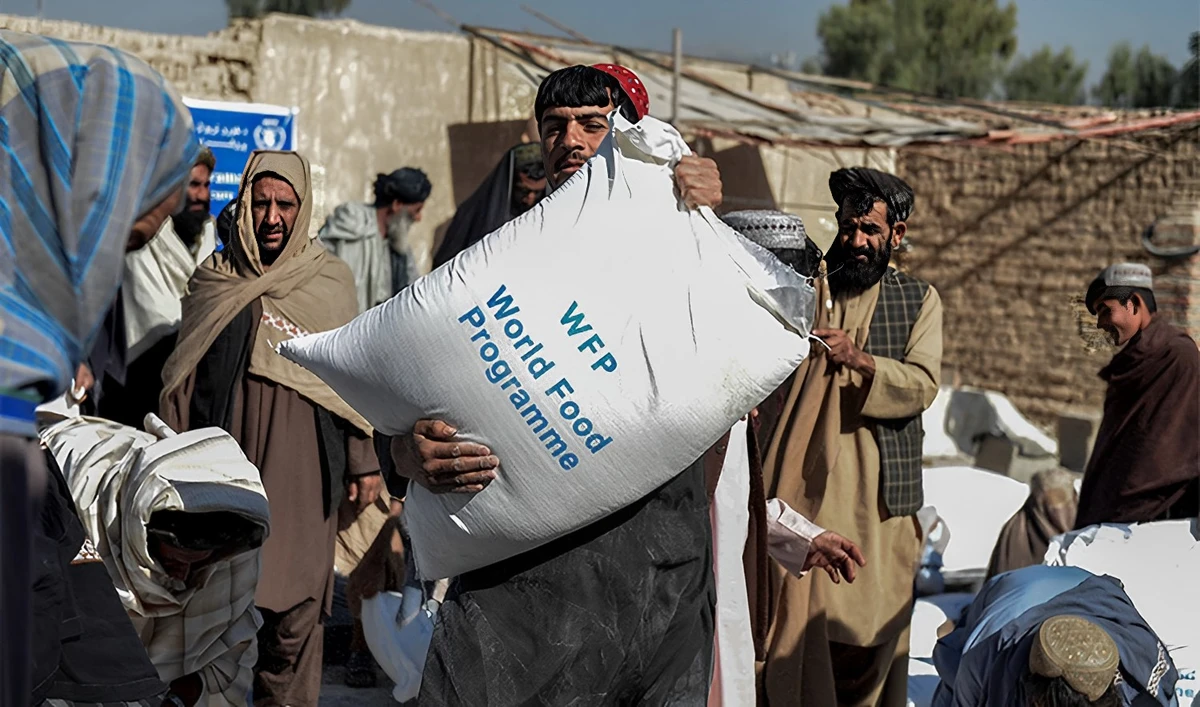 Afghan people carry sacks of food grains distributed as an aid by the World Food Programme (WFP) in Kandahar on October 19, 2021. (AFP)