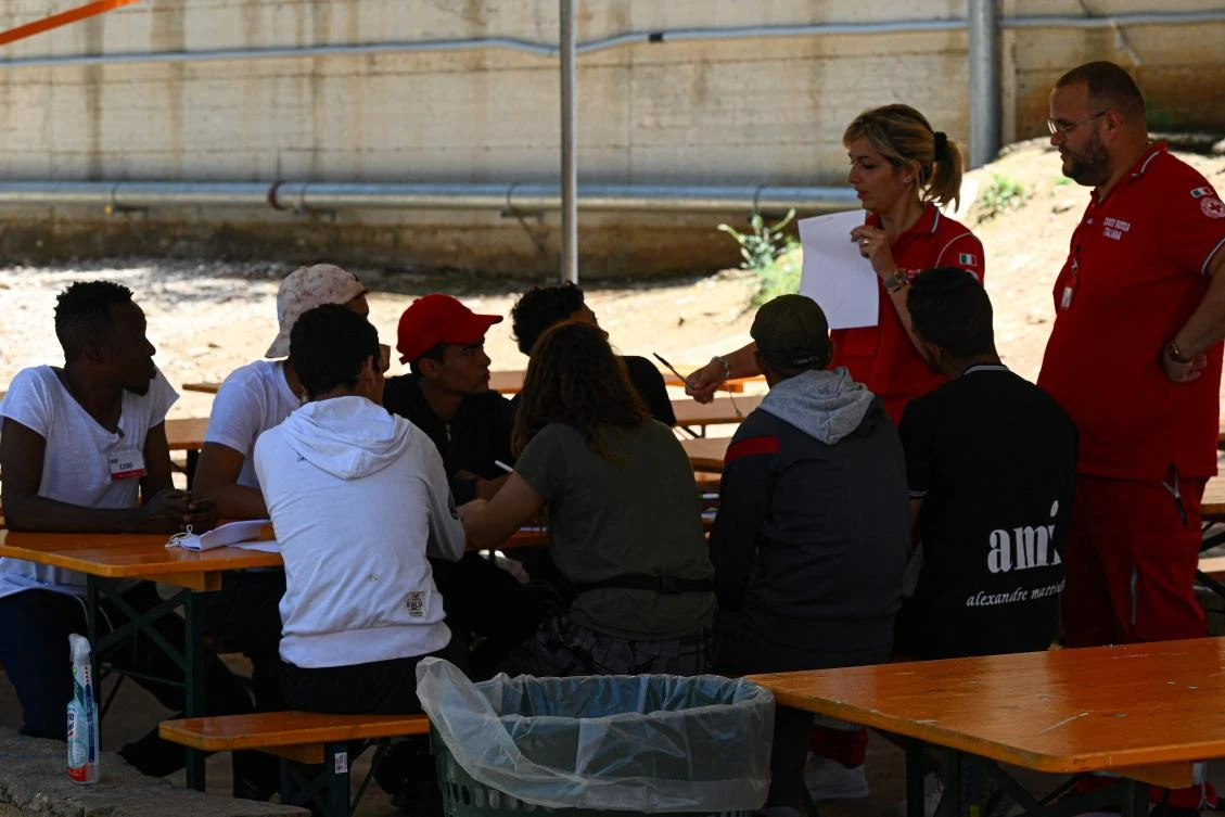 A volunteer of the Italian Red Cross (Rear R) gives a lesson of Italian language to young migrants on June 7, 2023 at the migrants hotspot on the island of Lampedusa, south of Sicily.. (AFP)