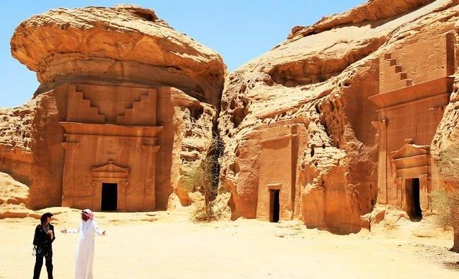 A foreign tourist listens to a Saudi guide near a Nabatean tombs complex in the desert archaeological site in Al Ula, northwest of Riyadh. (File/AP)