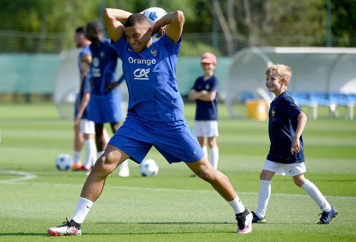 France's forward Kylian Mbappe demonstrates a throw in to a young fan during a training session in Clairefontaine-en-Yvelines on Wednesday, as part of the French national team's preparations for the upcoming UEFA Euro 2024 qualifying matches. (AFP)