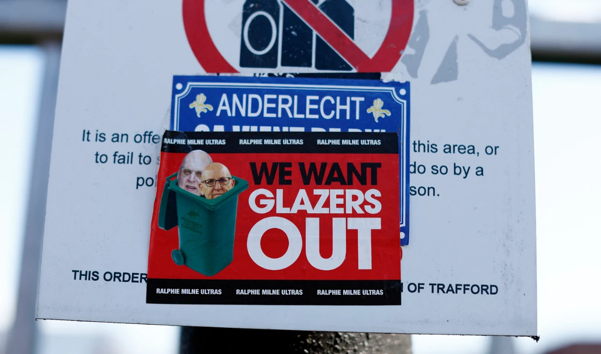 Manchester United has over 650 million fans worldwide, according to market research firm Kantar. A large number of them have been clamoring for a change of ownership. Photo shows sticker directed at Manchester United co owners Joel Glazer and Avram Glazer outside Old Trafford. (Reuters)
