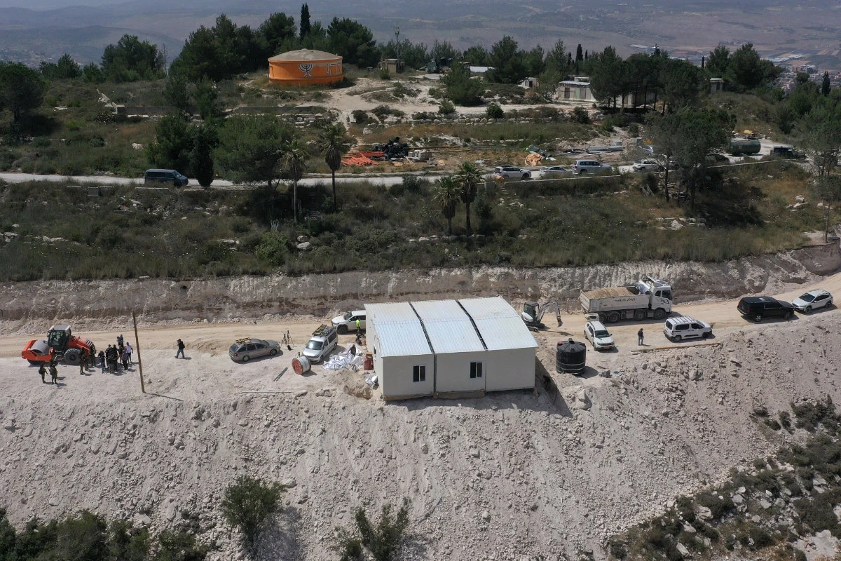An aerial view shows people around a portable building under construction at the Israeli settler outpost of Homesh, near the Palestinian village of Burqah, in the occupied West Bank, on May 29, 2023. (Photo by Menahem Kahana / AFP)