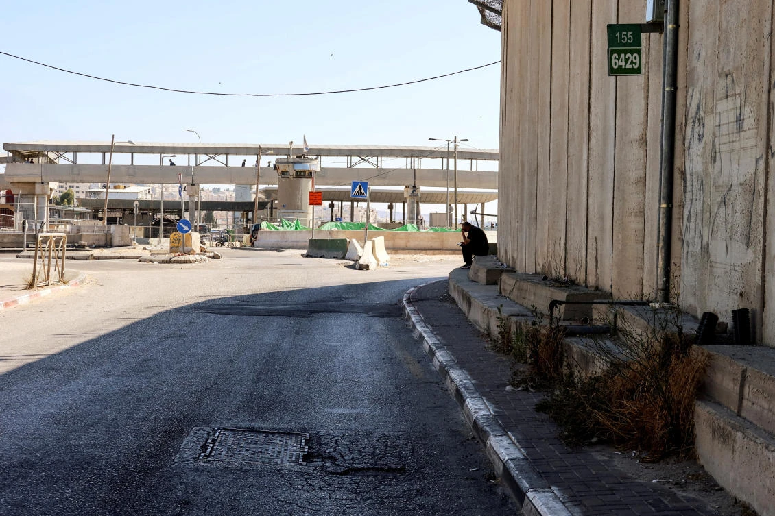 A man sits by the Qalandia checkpoint after, according to Israel's police, a suspected Palestinian gunman opened fire at the Israeli checkpoint in the occupied West Bank, wounding a security guard before he was shot dead. (Reuters)