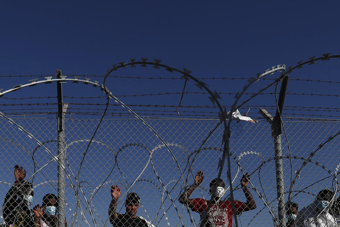 Migrants stand behind a fence inside a refugee camp in Kokkinotrimithia outside of capital Nicosia on Feb. 5, 2021. (AP/File)