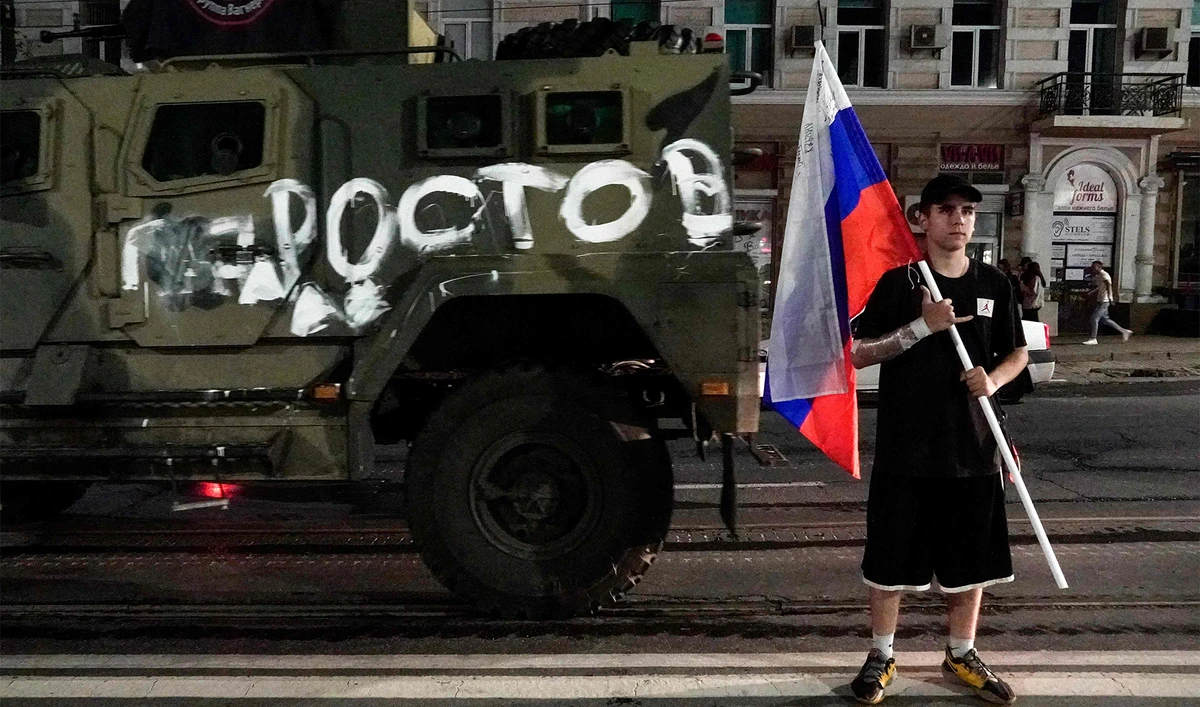 A man holds the Russian national flag in front of a Wagner group military vehicle with the sign read as "Rostov" in Rostov-on-Don late on June 24, 2023. (AFP)