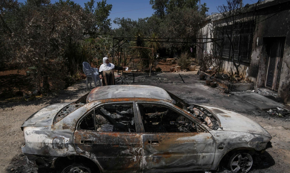 A Palestinian woman sits outside her torched home, days after it was set on fire by Jewish settlers, in the West Bank town of Turmus Ayya, on June 24, 2023. (AP)