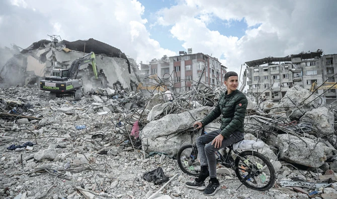 A young resident looks for belongings as the rubble of his house are being removed in Turkiye’s earthquake-hit mountainous southeast, in Antakya. (File/AFP)