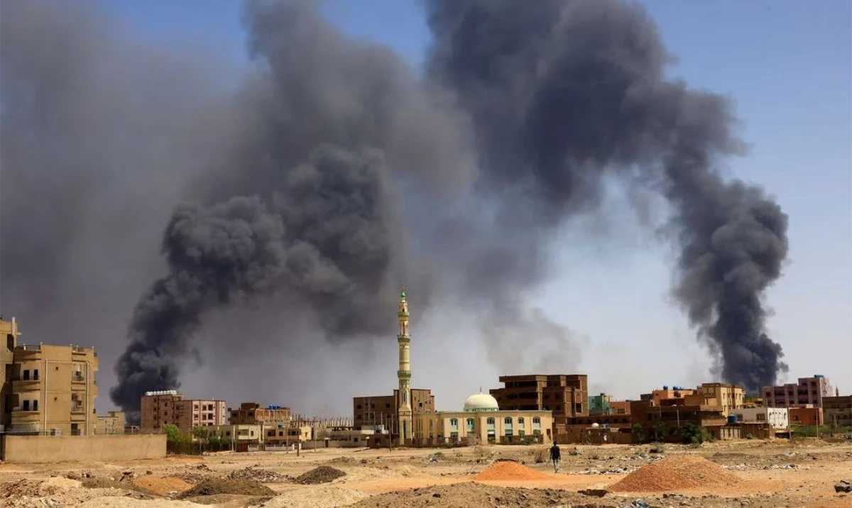 A man walks while smoke rises above buildings after aerial bombardment, during clashes in Khartoum North, Sudan. (Reuters)