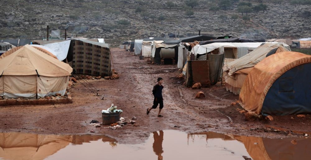An internally displaced Syrian boy walks through mud at Kafr Arouk camp, Idlib, Syria, Dec. 20, 2021. (Reuters)