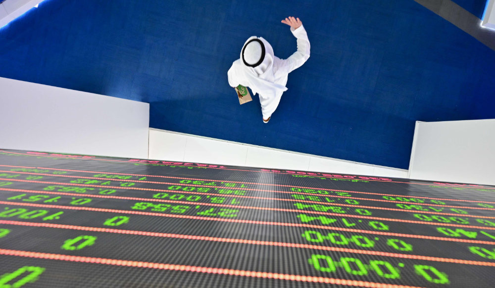 A trader walks by beneath a stock display board at the Dubai Stock Exchange in the United Arab Emirates. (AFP file photo)