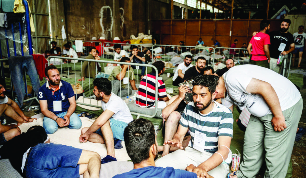 Migrants who were rescued at open sea off Greece along with other migrants after their boat capsized are seen inside a warehouse — used as shelter — at the port of Kalamata, Greece. (Reuters)