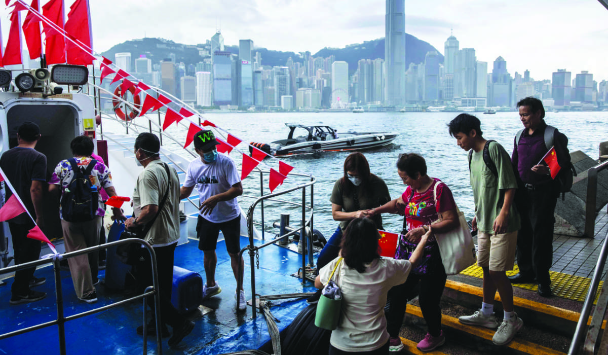 People board a boat in Hong Kong’s Tsim Sha Tsui waterfront amid celebrations marking the 26th anniversary of the city’s handover from Britain to China. (AFP)