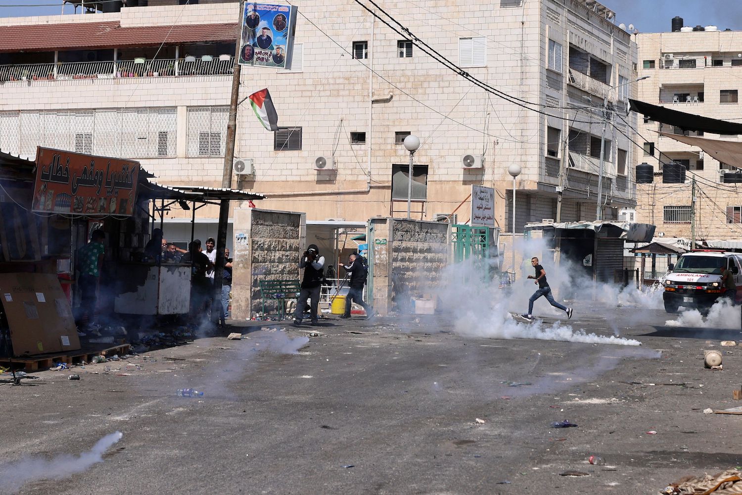 People flee falling tear gas canisters during an ongoing Israeli military operation in Jenin city in the occupied West Bank on July 4, 2023. (AFP)