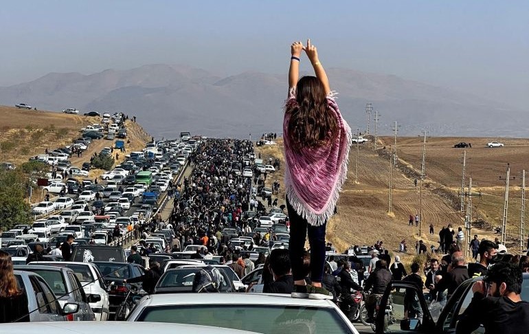A young woman stands on top of a car as thousands make their way toward Aichi cemetery in Saqez, Mahsa Amini’s home town in the Iranian province of Kurdistan, to mark 40 days since her death. (AFP)