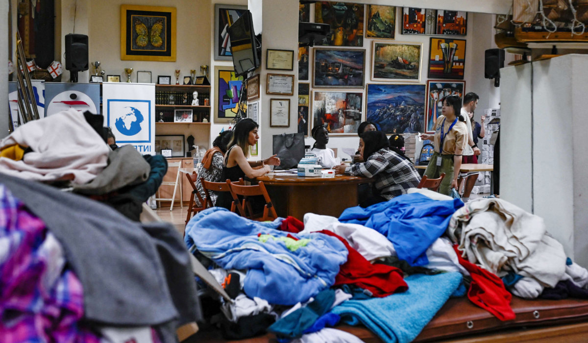 A picture taken on June 26, 2023, shows migrants receiving food and clothes from an NGO in Athens. (AFP)