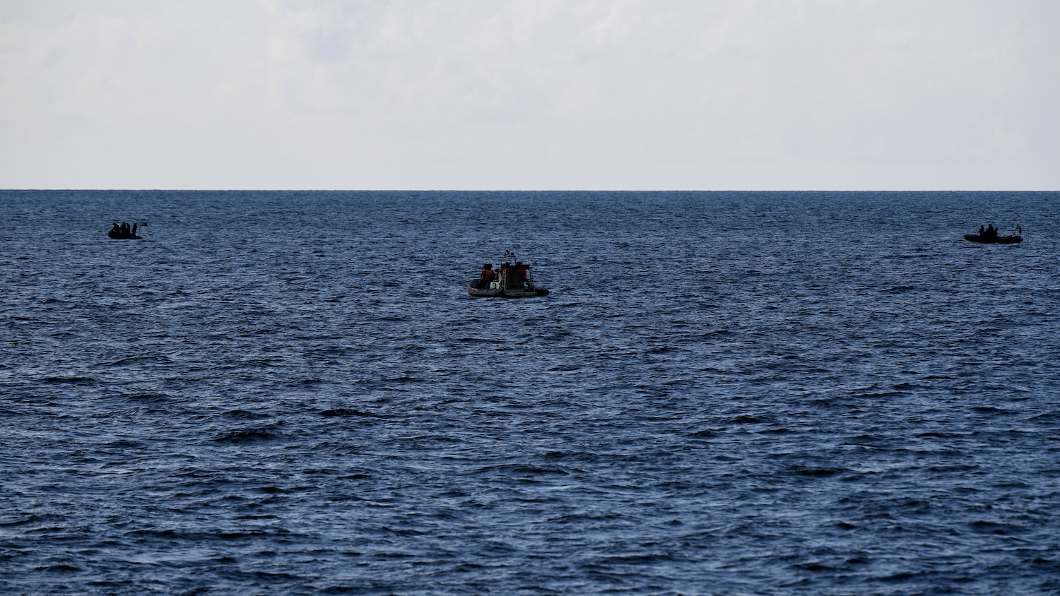 Chinese coast guard personnel (C) aboard their rigid hull inflatable boat observing Philippine coast guard personnel (L and R) conducting a survey in the waters of disputed South China Sea. (File/AFP)