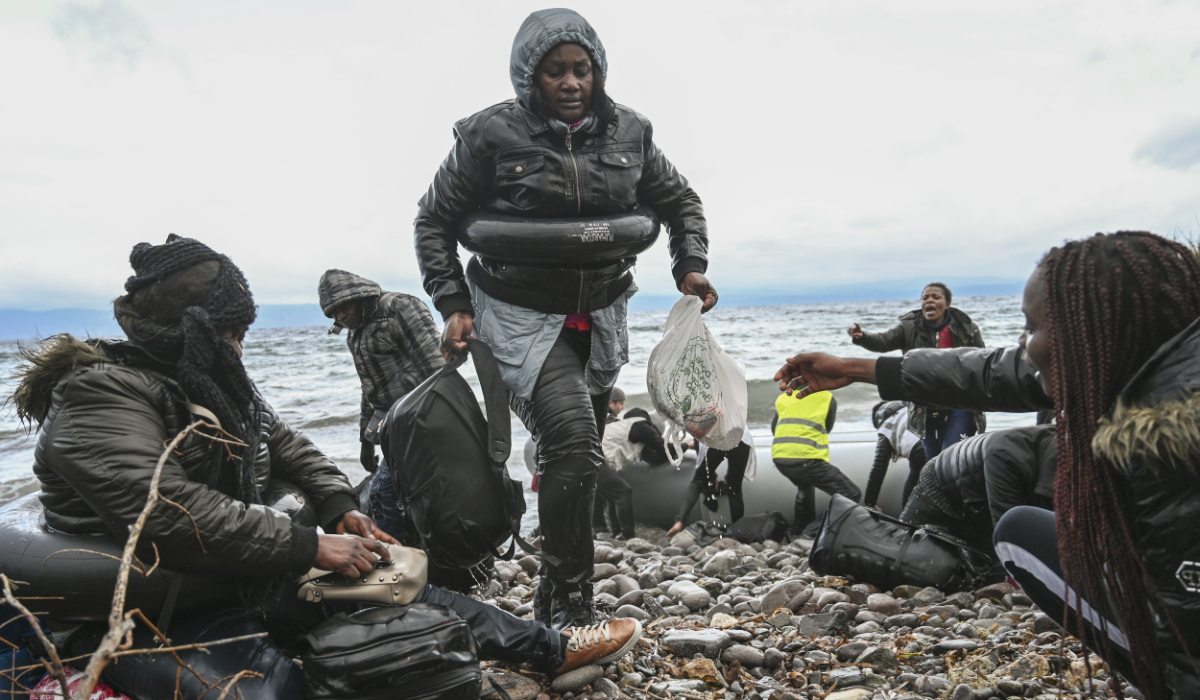 A woman carries her belongings as a dinghy transporting 27 refugees and migrants originating from Gambia and the Republic of Congo lands in Lesbos island after they were rescued by a war ship during their sea crossing between Turkey and Greece on February 29, 2020. (AFP)