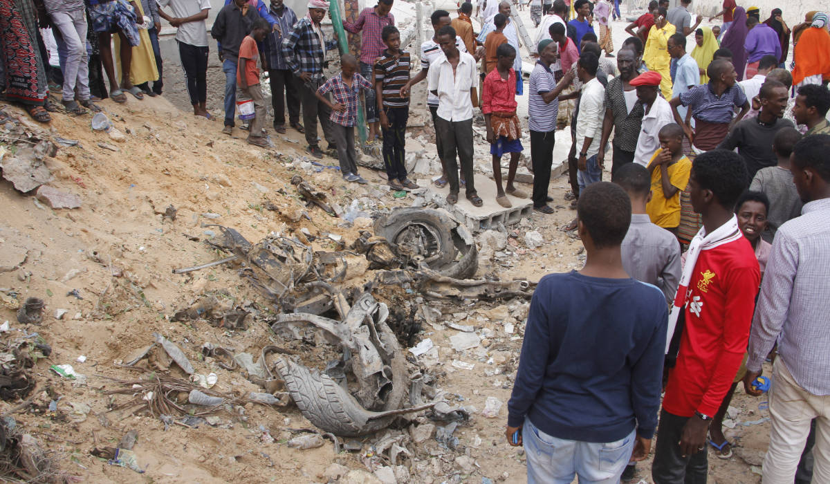Somalis gather near the destroyed car after a car bomb detonated in Mogadishu, Somali, Monday, July 8, 2019. (AP)