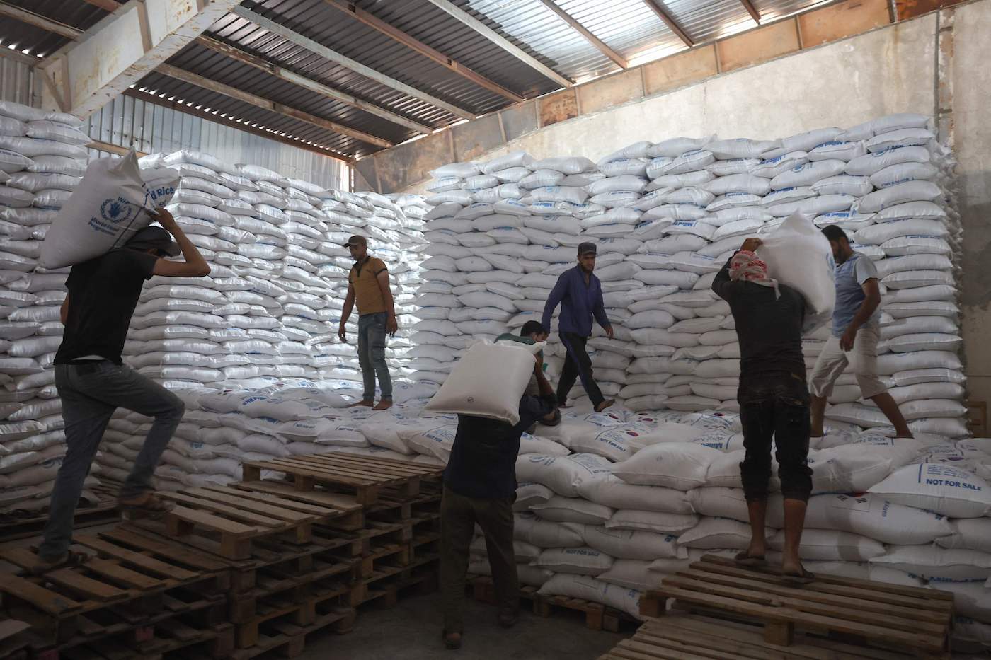 Workers unload bags of aid at a warehouse near the Syrian Bab Al-Hawa border crossing with Turkey, on July 10, 2023. (AFP)