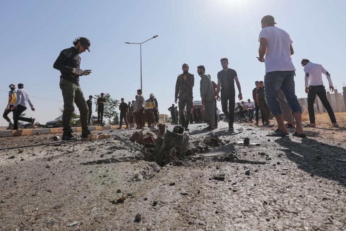 Passersby and gunmen gather at the site of a reported drone strike in Bzaah town near Al-Bab in Syria’s Aleppo governorate on July 7, 2023. (AFP)