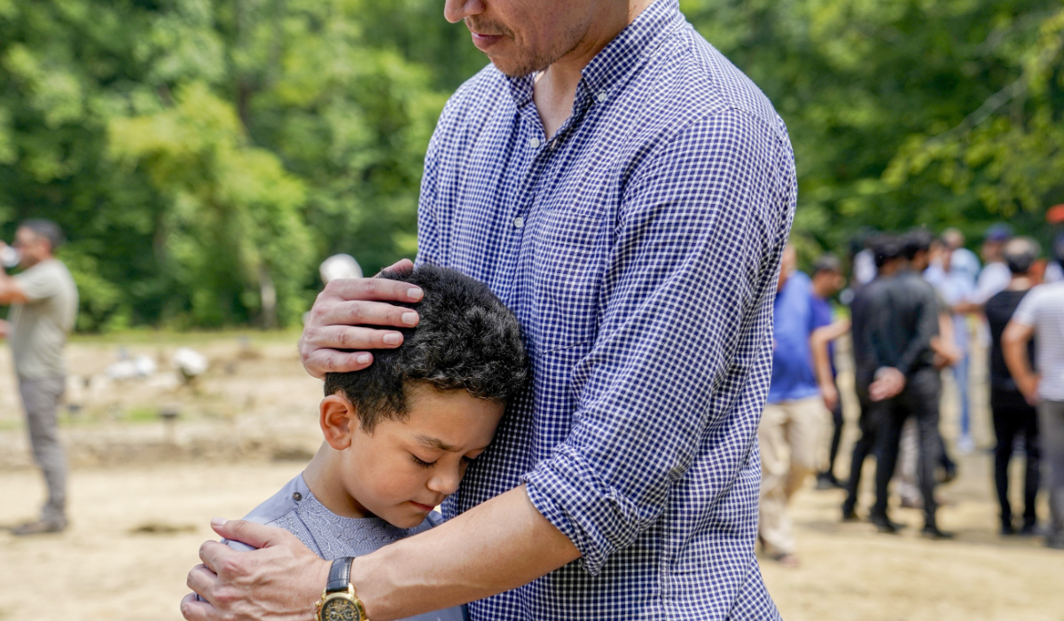 Asem Ahmad Yar, 8, son of Nasrat Ahmad Yar, 31, is comforted by a family friend during the funeral service for his father at the All Muslim Association of America cemetery on Saturday, July 8, 2023 in Fredericksburg, Va. (AP)