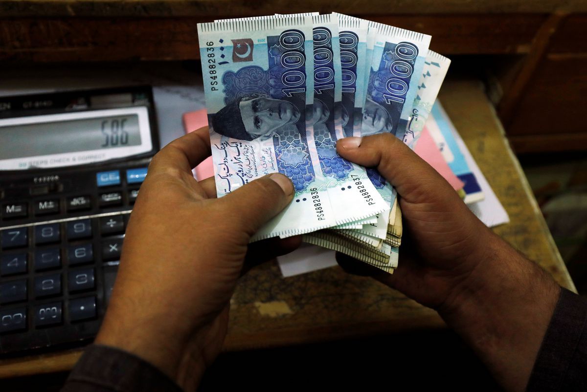 A trader counts Pakistani rupee notes at a currency exchange booth in Peshawar, Pakistan. (File/Reuters)