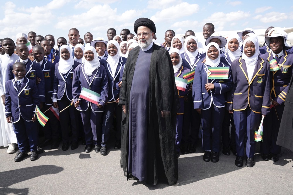 Iran’s President Ebrahim Raisi poses for a photograph with children on Thursday upon his arrival at Robert Mugabe airport in Harare, Zimbabwe. (AP)