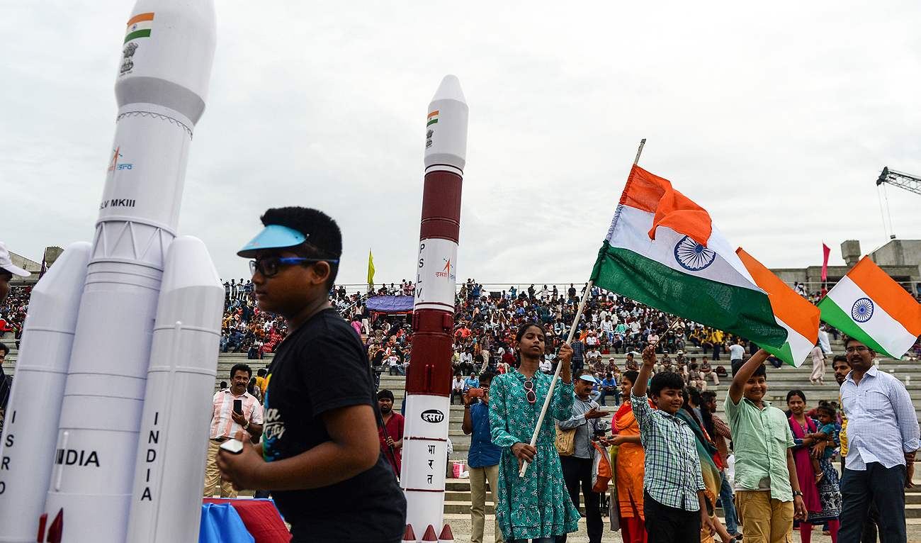 In this photo, taken on July 22, 2019, Students wave Indian national flags as the Indian Space Research Organisation's (ISRO) Chandrayaan-2 (Moon Chariot 2), with on board the Geosynchronous Satellite Launch Vehicle (GSLV-mark III-M1), has been launched in Sriharikota in the state of Andhra Pradesh. (AFP/File)