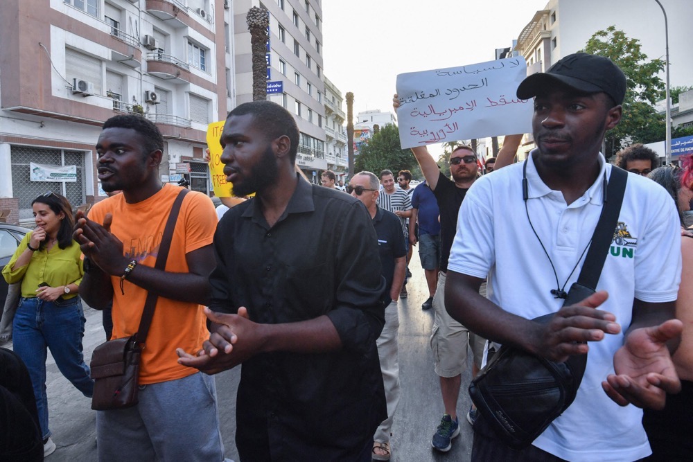 Demonstrators lift placards and chant anti-racism slogans during a protest in Tunis on July 14, 2023. (AFP)