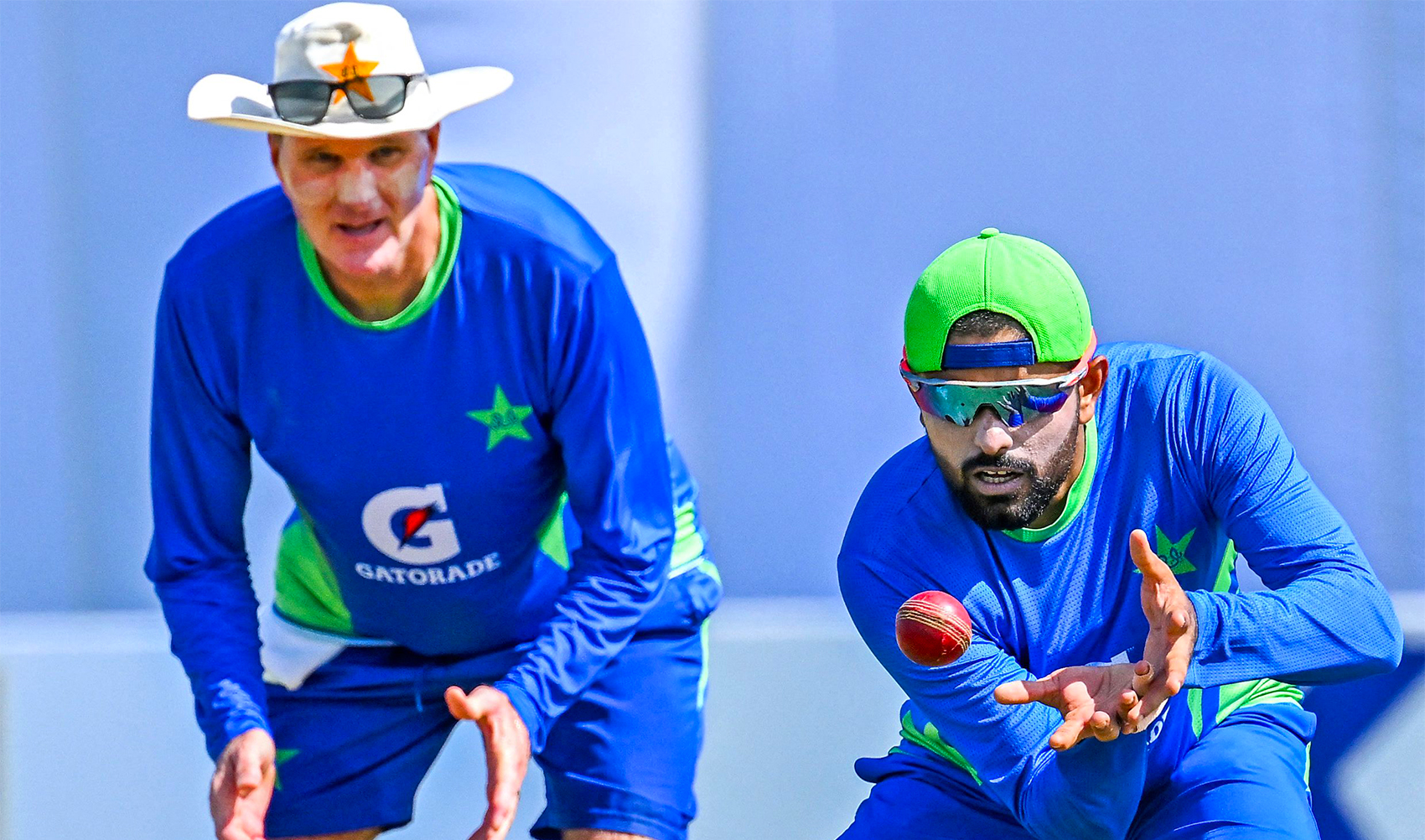 Pakistan's captain Babar Azam (R) catches a ball as coach Grant Bradburn looks on during a practice session at the Galle International Cricket Stadium in Galle on July 15, 2023, on the eve of their first cricket Test match against Sri Lanka. (Photo by Ishara S. KODIKARA / AFP)