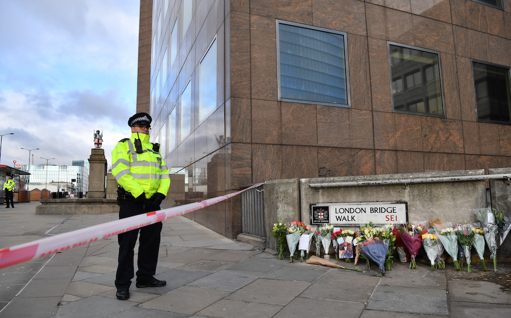 A police officer stands at a cordon beside floral tributes left close to London Bridge following the November 29, 2019 deadly terror incident. (AFP)