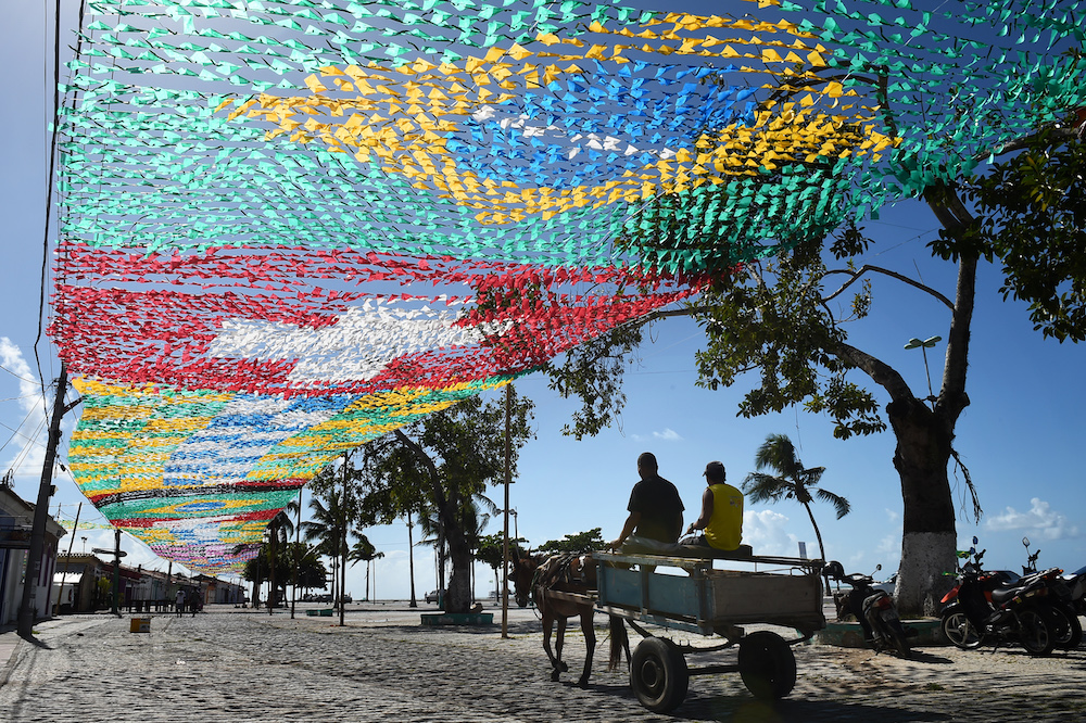 Above, a canopy of national flags of participating countries festoon Porto Seguro in Brazil when it hosted the 2014 FIFA World Cup. The football-crazy country has received backing from Arab investors, ensuring an ‘organizational revolution’ for the sport. (AFP)