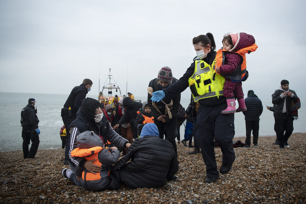 A member of the UK Border Force (R) helps child migrants on a beach in Dungeness, on the south-east coast of England, on November 24, 2021 after being rescued while crossing the English Channel. (AFP)