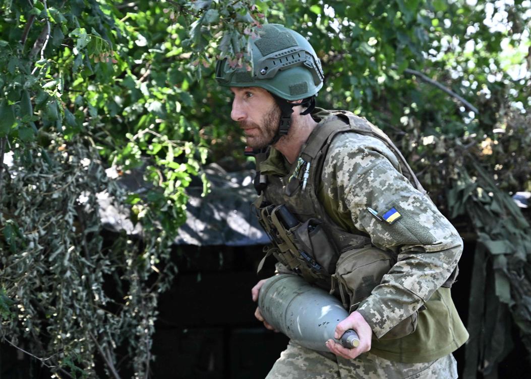 A Ukrainian artilleryman carries a 152 mm shell for artillery at a position on the front line near Bakhmut, eastern Ukraine, on July 20, 2023, amid the Russian invasion of Ukraine. (AFP)