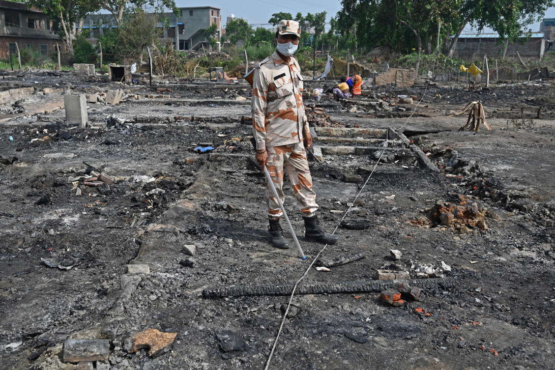 An Indo Tibet Border Police (ITBP) personal inspects the ground around the charred remains of a Rohingya camp where a fire incident broke out earlier today in New Delhi on June 13, 2021. (AFP)