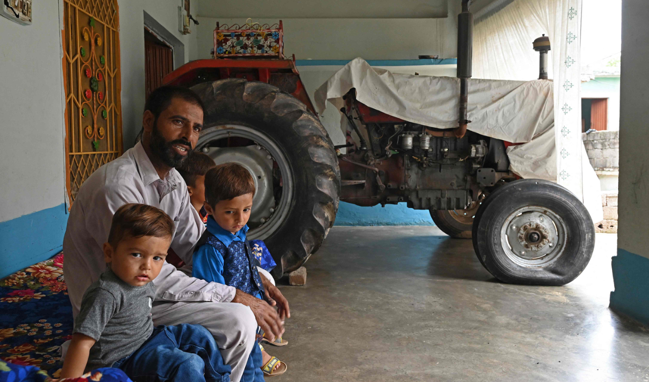 In this picture taken on July 18, 2023, Pakistani worker Muhammad Naeem Butt sits with his children at his home in Khuiratta. (AFP)