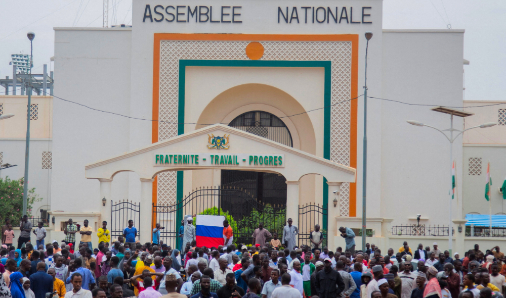 Hundreds of supporters of the coup gather and hold a Russian flag in front of the National Assembly in the capital Niamey, Niger July 27, 2023. (Reuters)