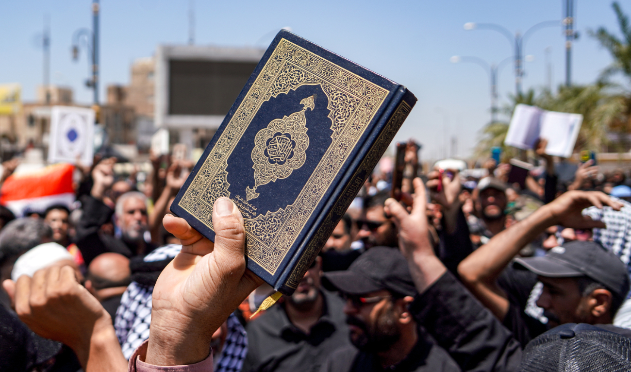 A demonstrator holds a copy of the Holy Qur’an during a rally after the weekly Friday prayers denouncing the burning of the Qur’an in Sweden, in Iraq on July 21, 2023. (AFP)