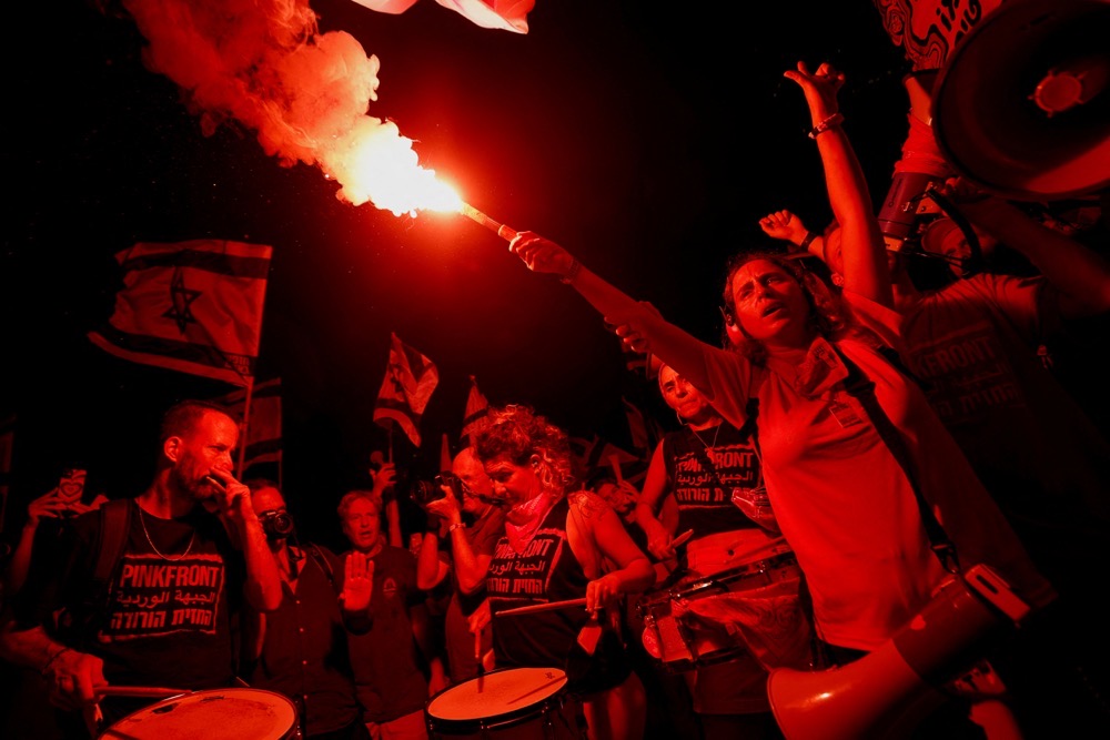 A protester holds a flare during a demonstration against Israeli Prime Minister Benjamin Netanyahu and his nationalist coalition government's judicial overhaul. (Reuters)