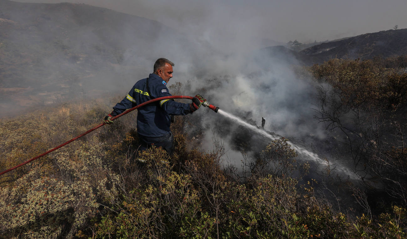 A firefighter tries to extinguish a wildfire burning near the village of Asklipieio, on the island of Rhodes, Greece, July 27, 2023. (Reuters)