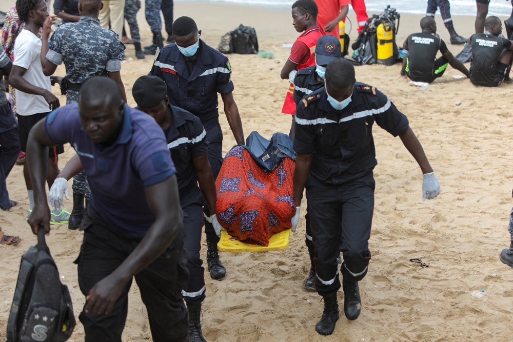 Firefighters transport a body away from the beach of Ouakam, where a boat transporting migrants, attempting irregular immigration, has run aground off the coast, Dakar, Senegal, July 24, 2023. (Reuters)