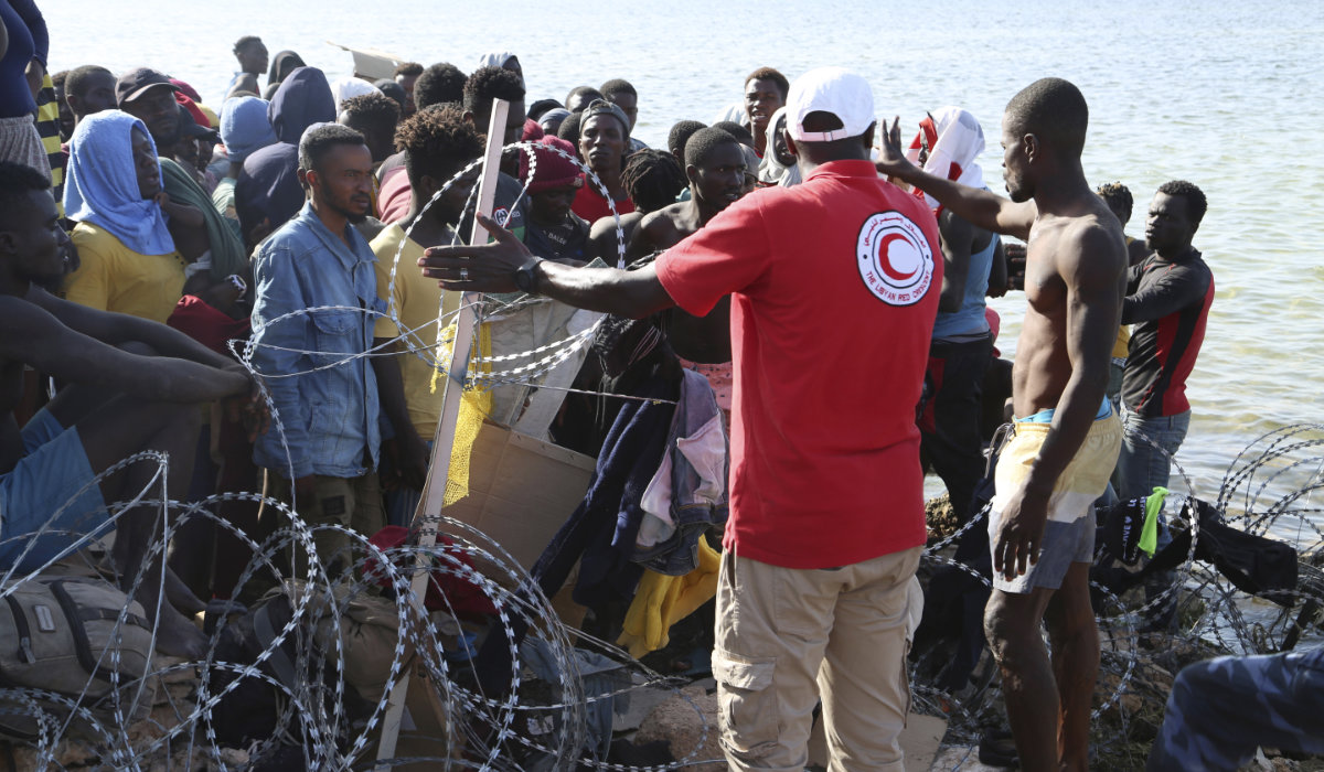 Migrants gather near the Libyan-Tunisia border, as Libyan security forces and Libyan Red Cross workers distribute food aid to them on Sunday, July 23, 2023. (AP)