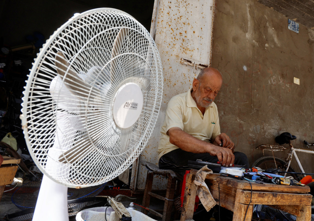 A Palestinian, Mustafa Abdou, repairs a fan in his shop amid a heatwave at the Shati refugee camp in Gaza City, July 25, 2023. (REUTERS)
