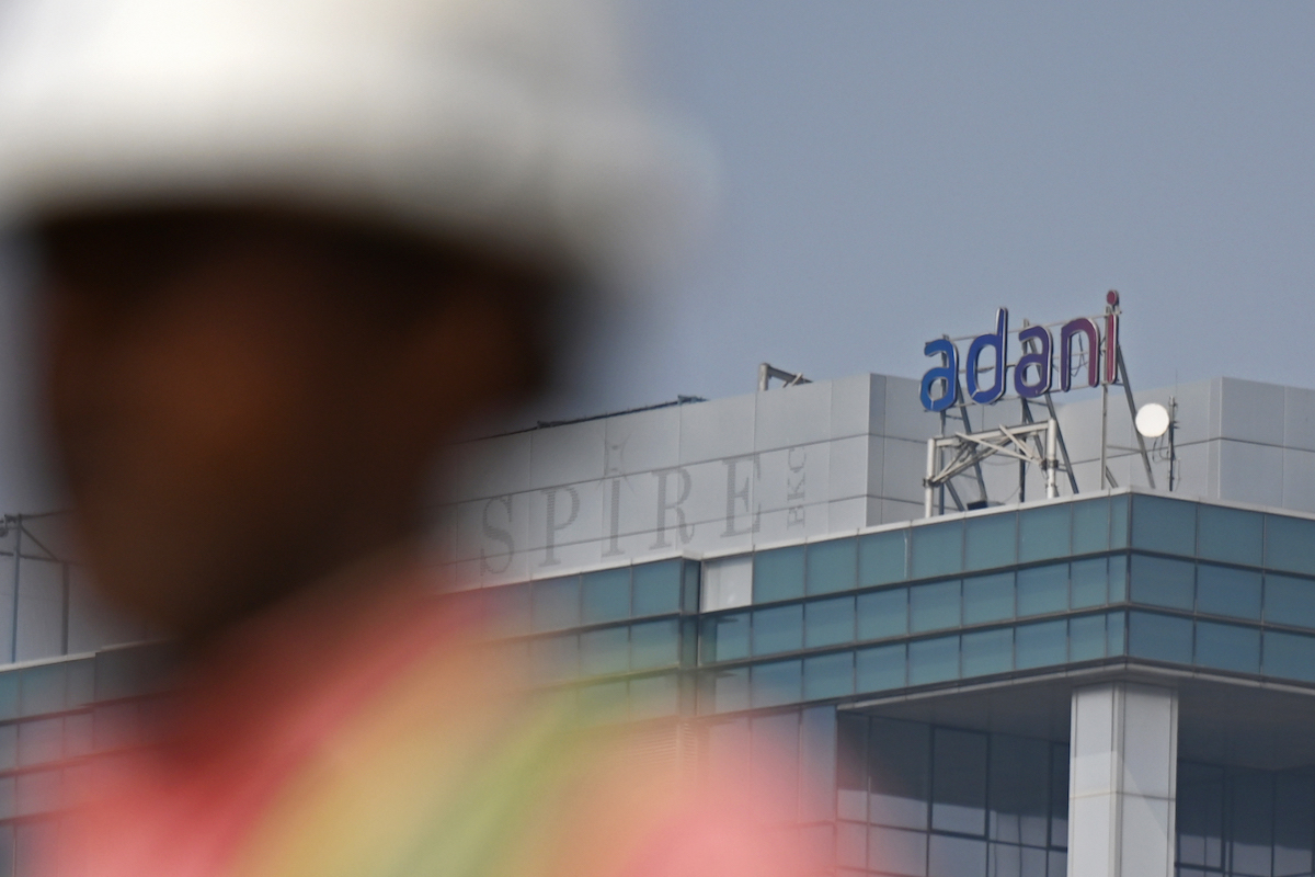 A construction worker walks past Adani company’s signage on a corporate building in Mumbai. (File/AFP)