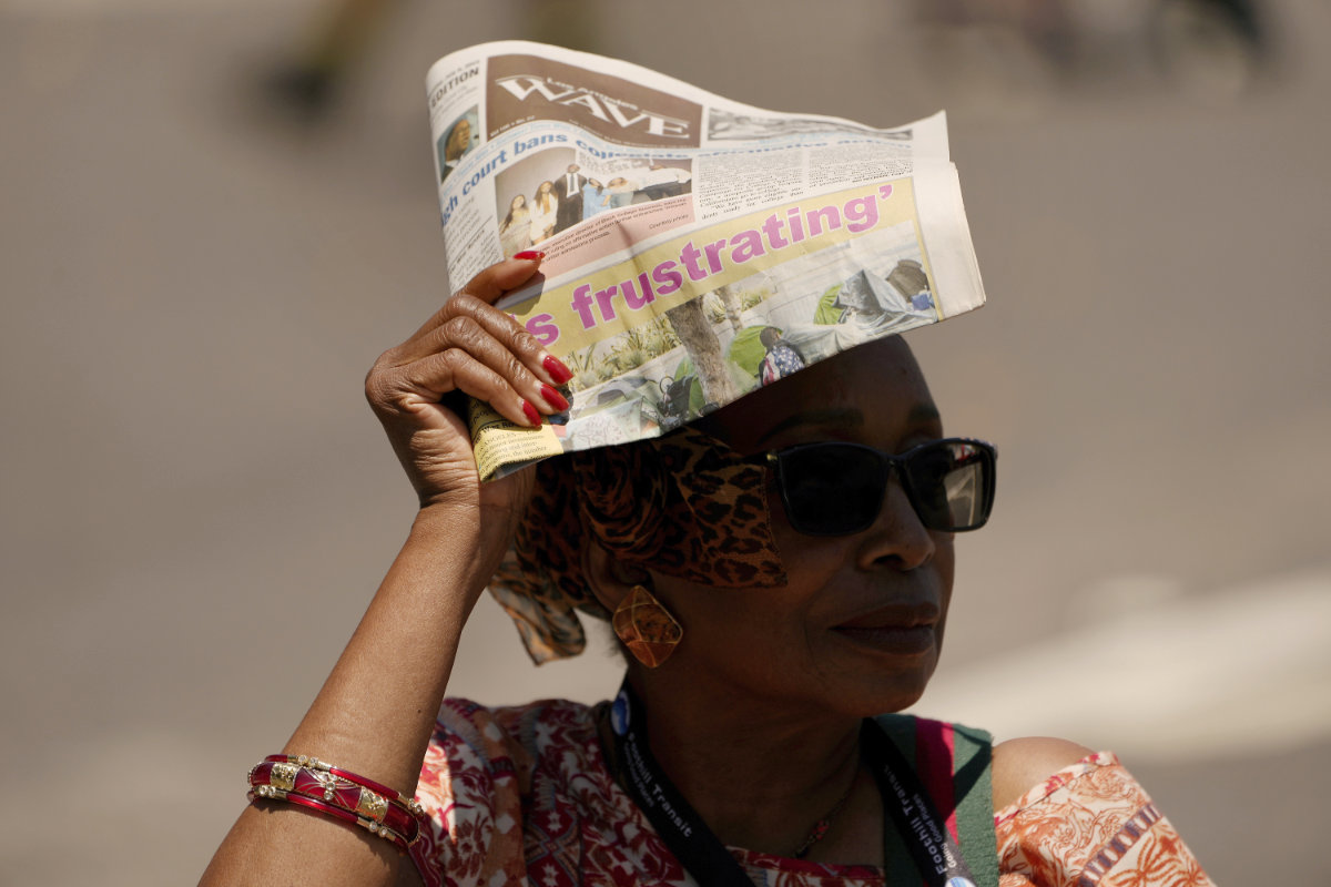 A woman shields herself from the sunlight with a copy of the Los Angeles Wave newspaper, July 15, 2023, in the Leimert Park neighborhood of Los Angeles. (AP)
