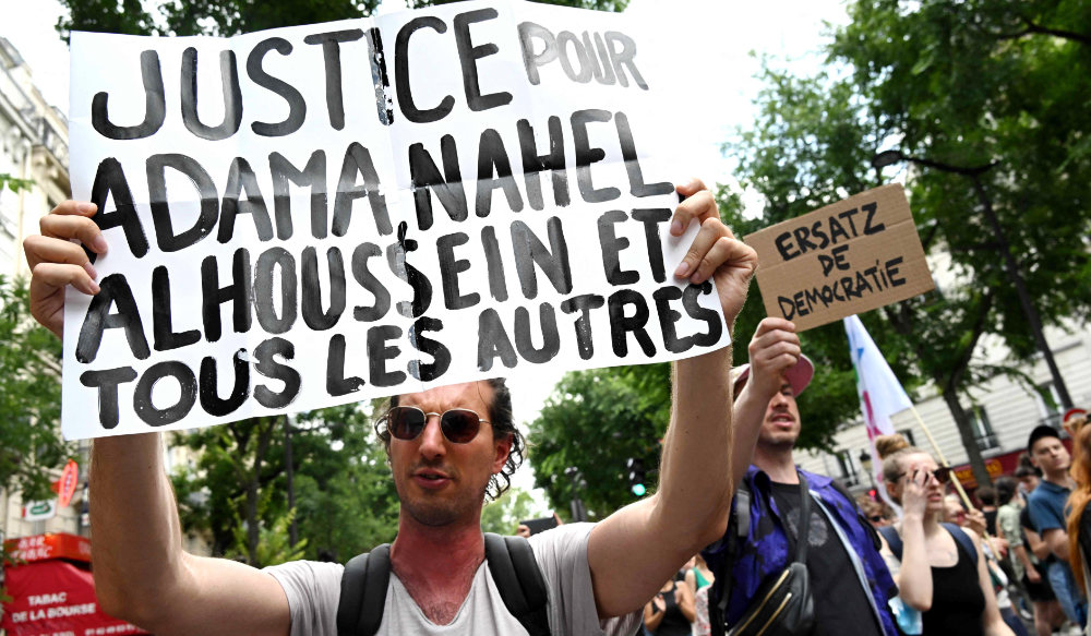 A participant holds a placard during the "March for Adama Traore" - seven years after his death in Paris on July 8, 2023. (AFP)