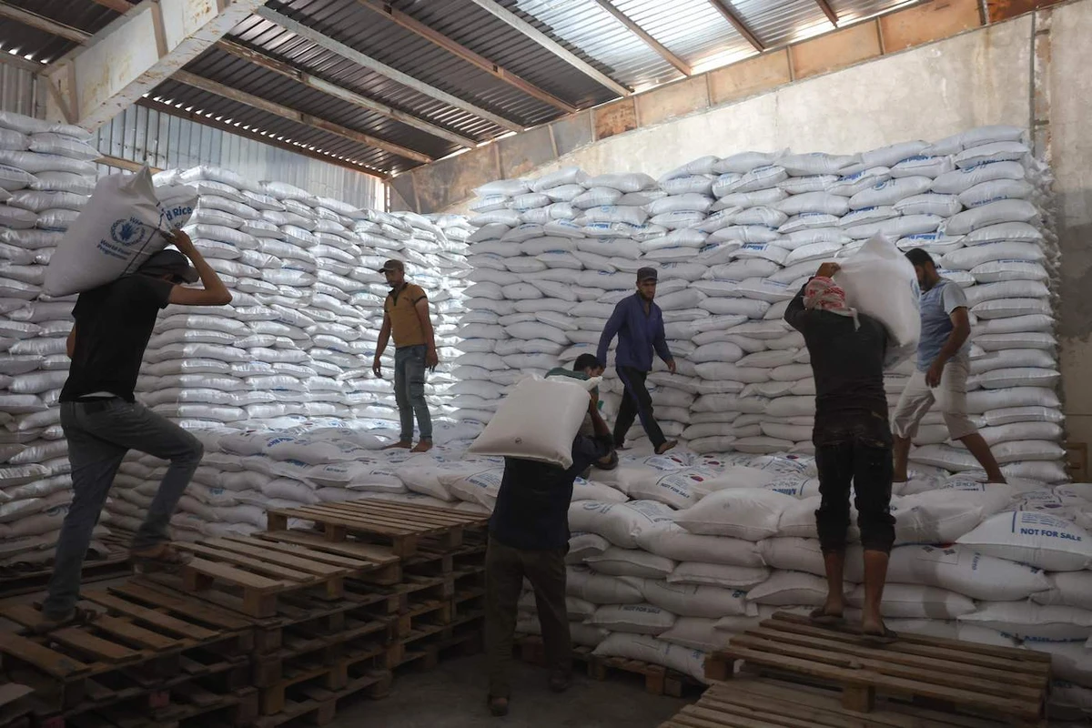 Workers unload bags of aid at a warehouse near the Syrian Bab Al-Hawa border crossing with Turkey, on July 10, 2023. (AFP)