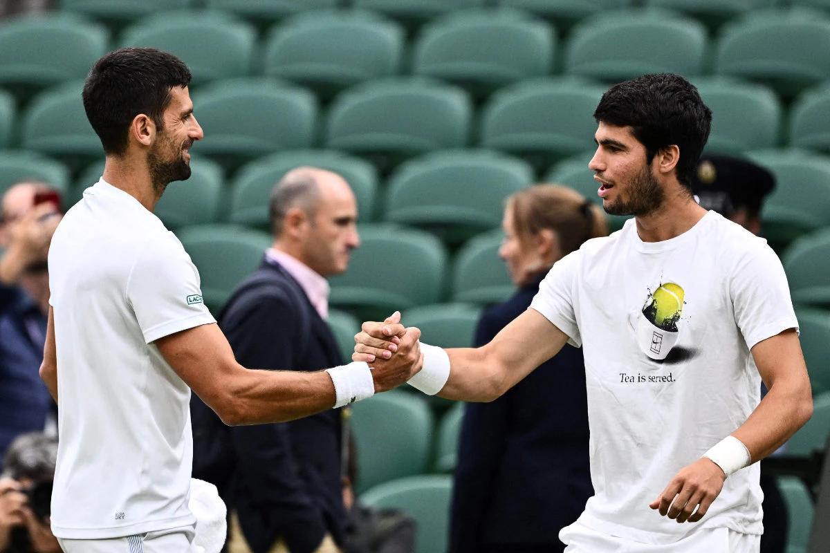 Serbia's Novak Djokovic (L) shakes hands with Spain's Carlos Alcaraz during a practice session ahead of their Wimbledon men's singles semi-finals tennis matches on July 14, 2023. (AFP)