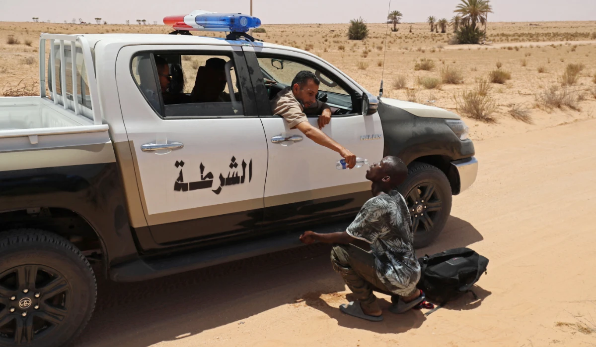 A Libyan border guard gives water to a migrant during a rescue operation in an uninhabited area near the border town of Al-Assah on July 16, 2023. (AP)